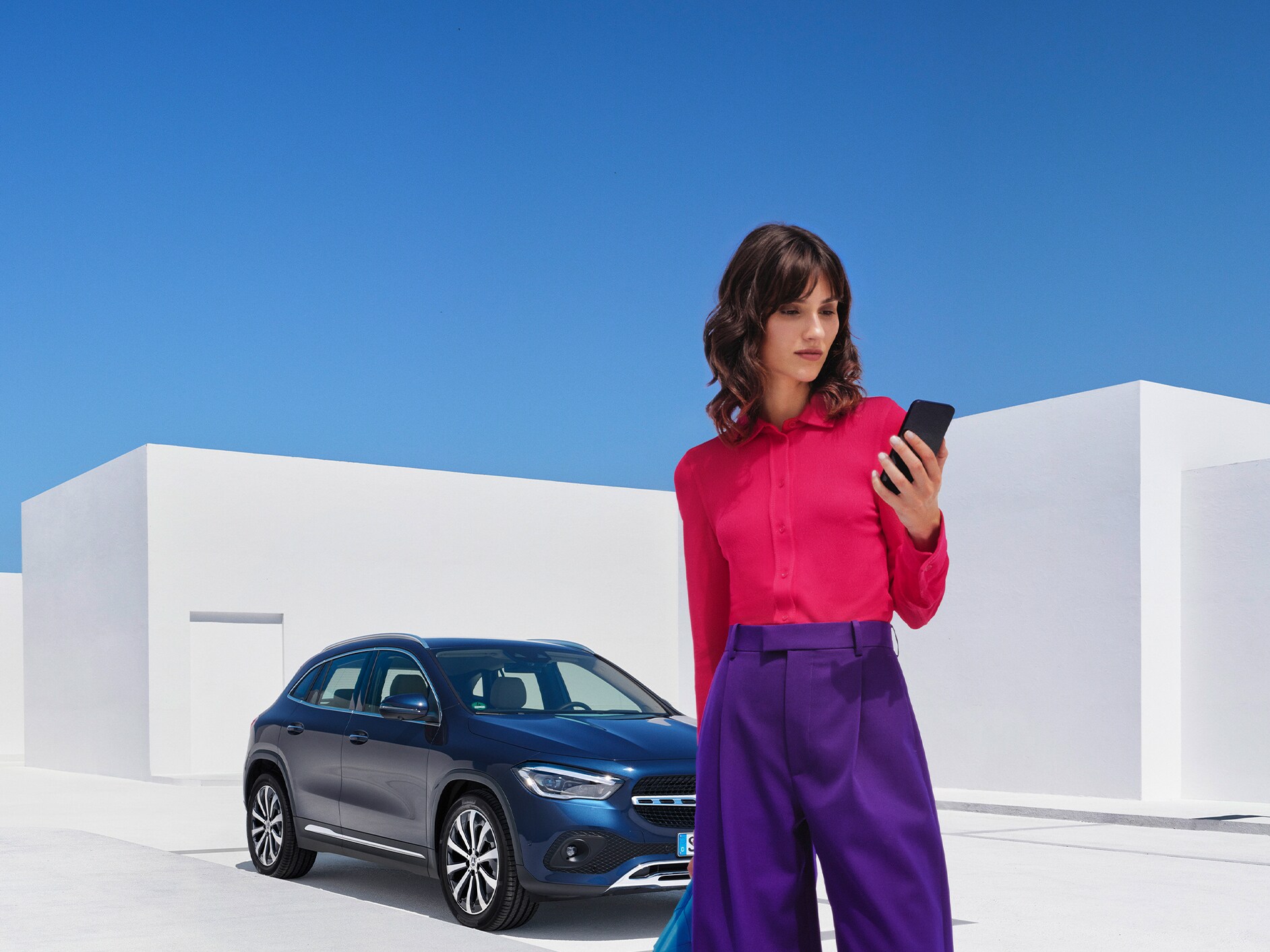 Eine Frau stellt per Mercedes me App auf ihrem Smartphone eine Verbindung mit ihrem Mercedes-Benz her.