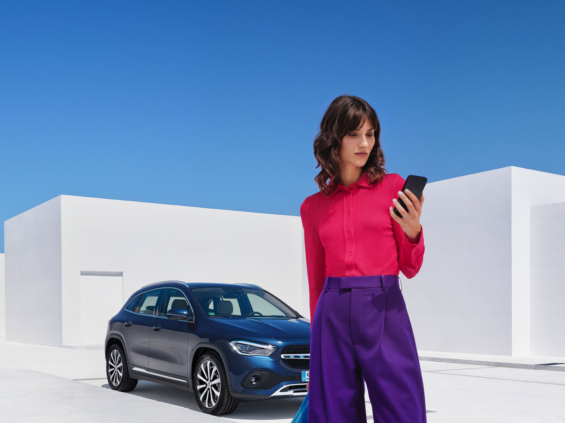 Eine Frau verbindet sich per Smartphone, der Mercedes me App und Ihrer Mercedes me ID mit ihrem Mercedes Benz.