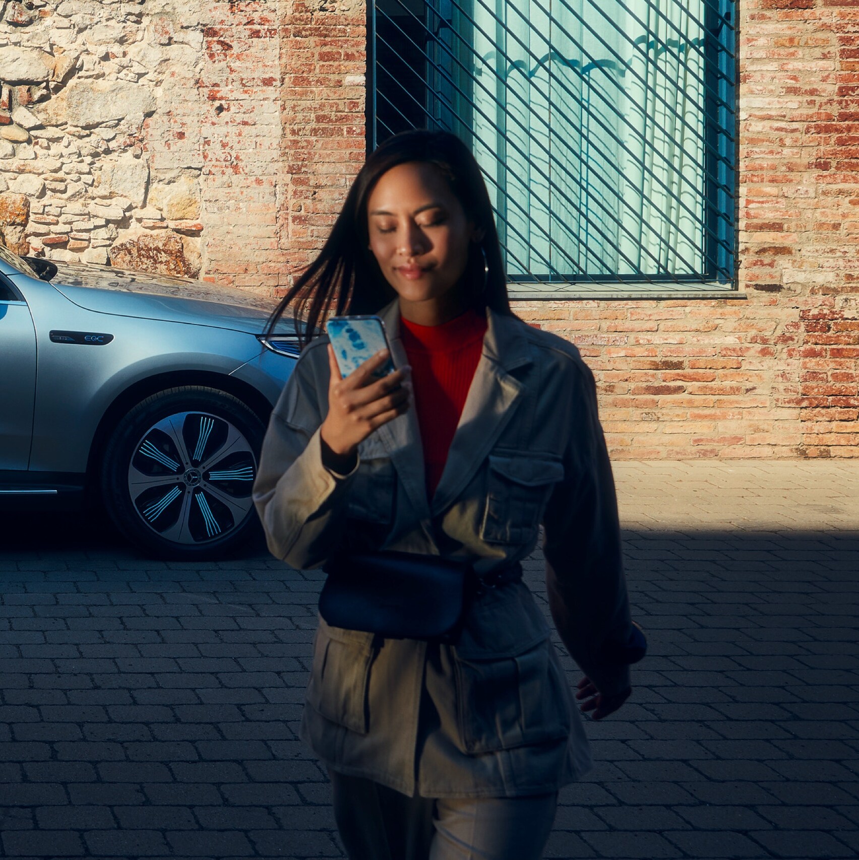 Eine Frau ist mit dem Smartphone per Digitalen Extras mit ihrem Mercedes-Benz verbunden.