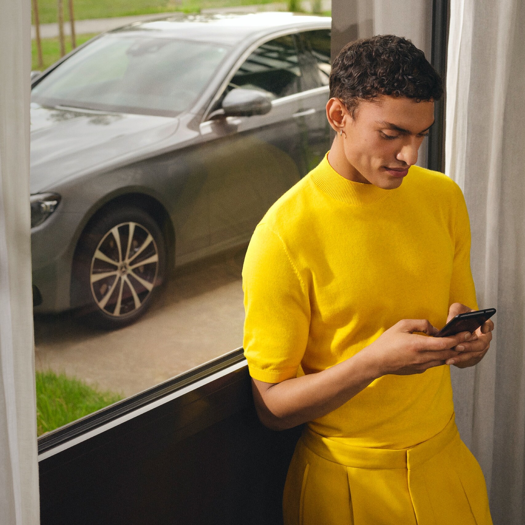 Ein Mann ist per Digitalen Extras mit dem Smartphone mit seinem Mercedes-Benz verbunden.