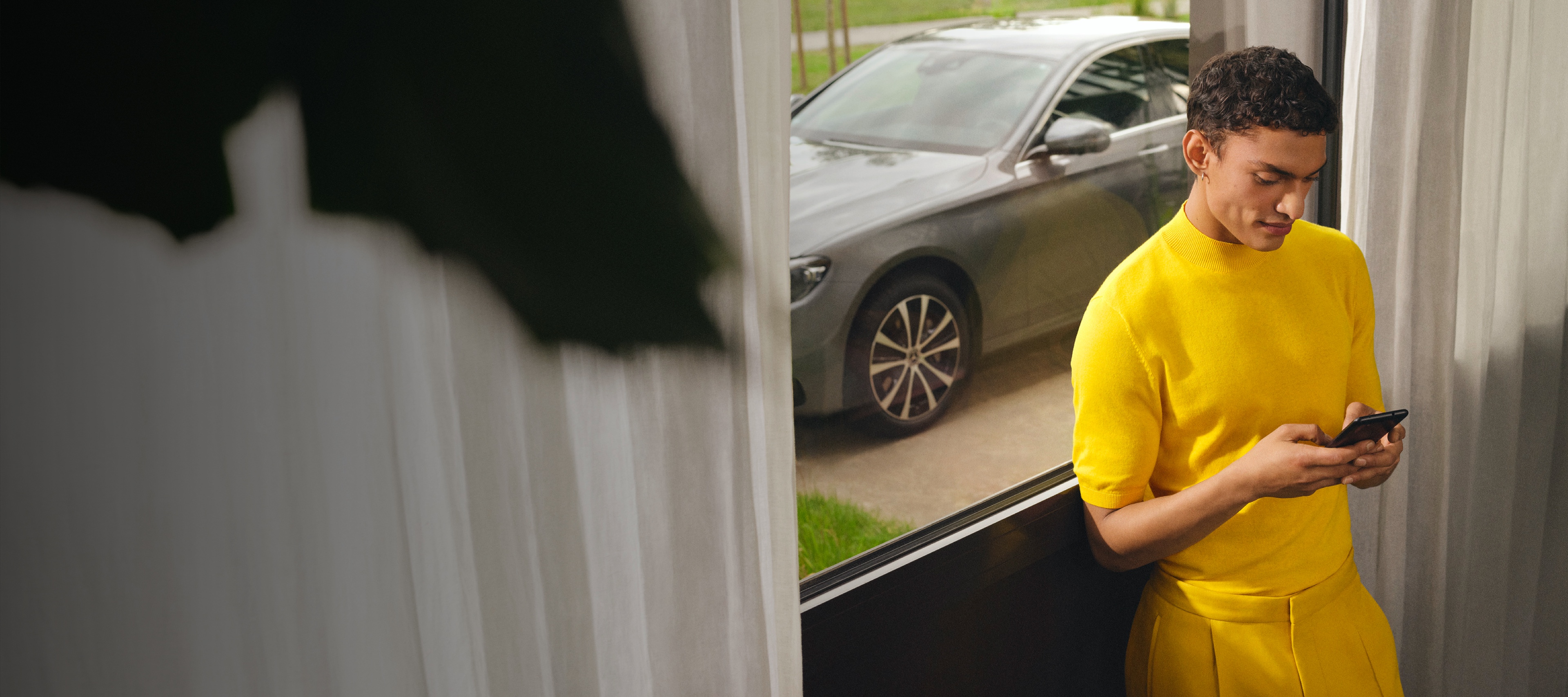 Ein Mann ist per Digitalen Extras mit dem Smartphone mit seinem Mercedes-Benz verbunden. Ein Mann ist per Digitalen Extras mit dem Smartphone mit seinem Mercedes-Benz verbunden.